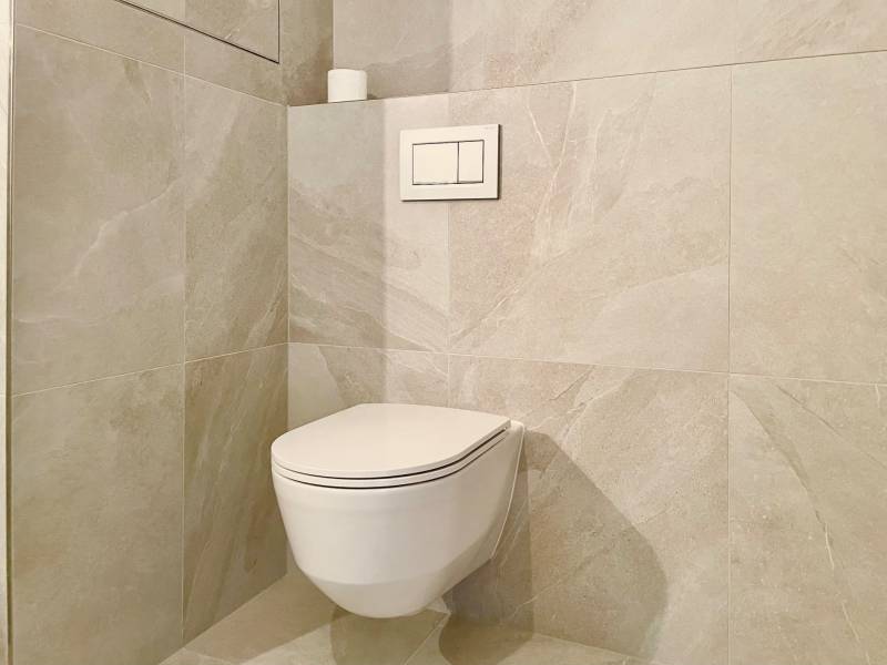 Bathroom in a 2-room apartment with a wall-hung toilet and large-format tiles.