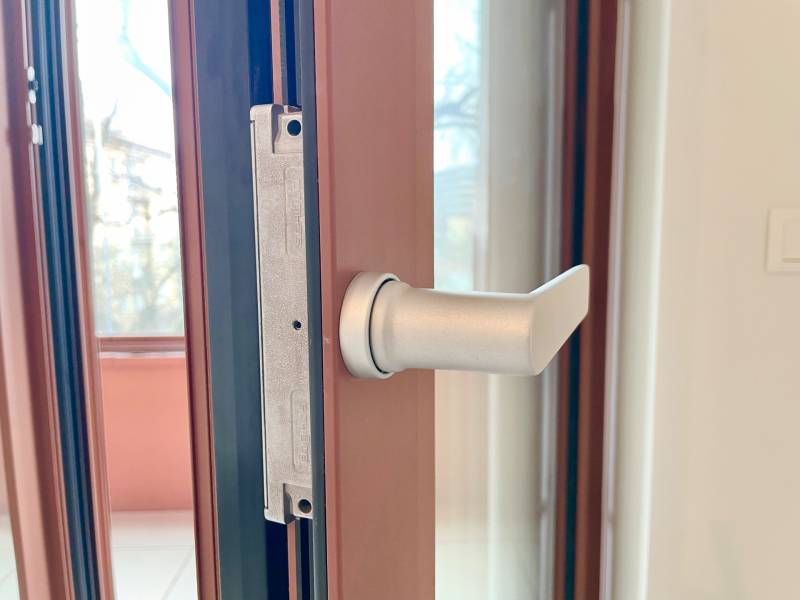 Detail of a metal door handle in a 2-room apartment with a view outside.