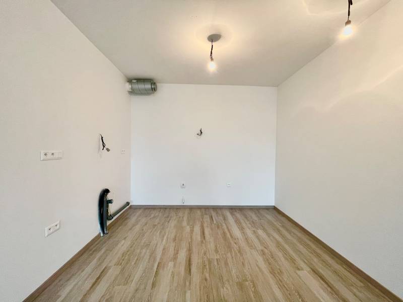 Empty room with wood-patterned flooring, ready to be furnished, 2-room apartment.