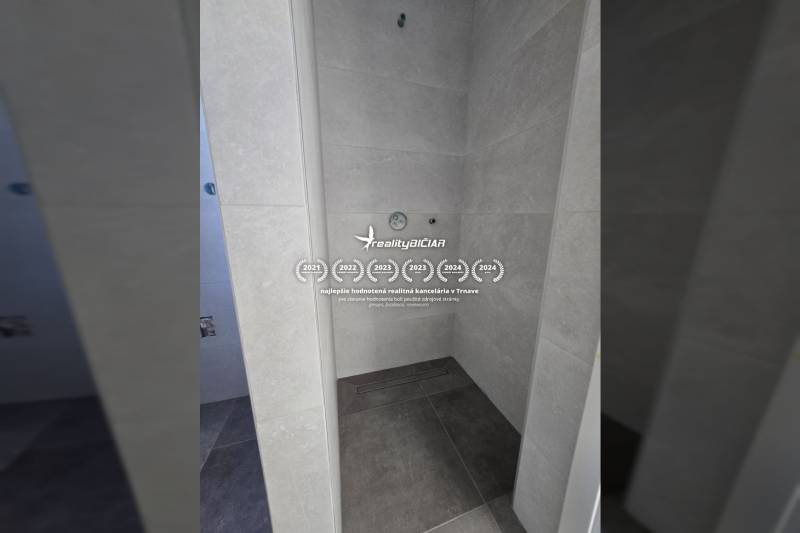 A shower enclosure in a family house, with dark tiles and light wall tiles.