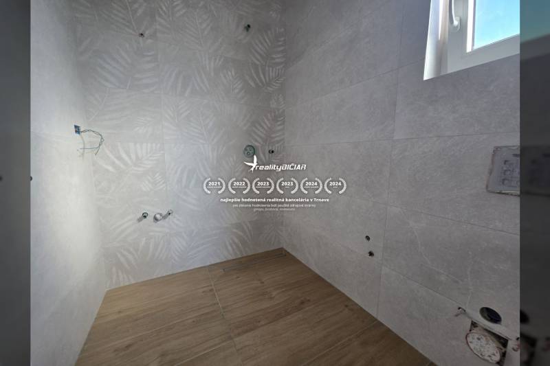 A bathroom in a family house with a wooden decor floor and leaf-patterned tiles.