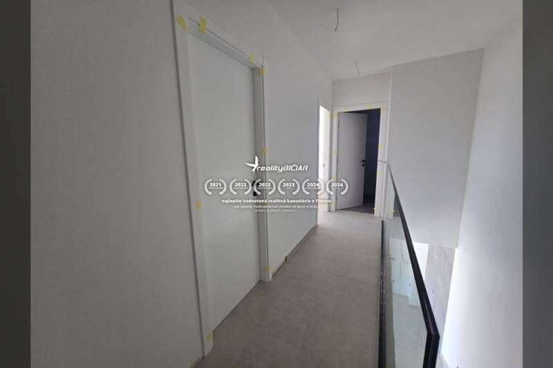 A hallway in a family house with white doors and glass railing.