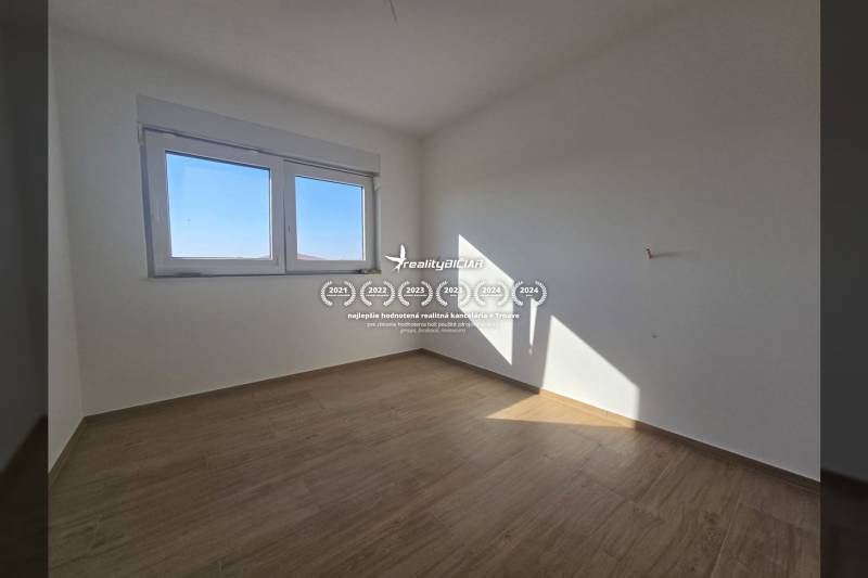 A room in a family house with a large window and a wooden decor floor.