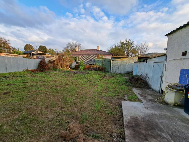 A garden at a family house on Mechenice Street in Podhorany, surrounded by fences and grass.