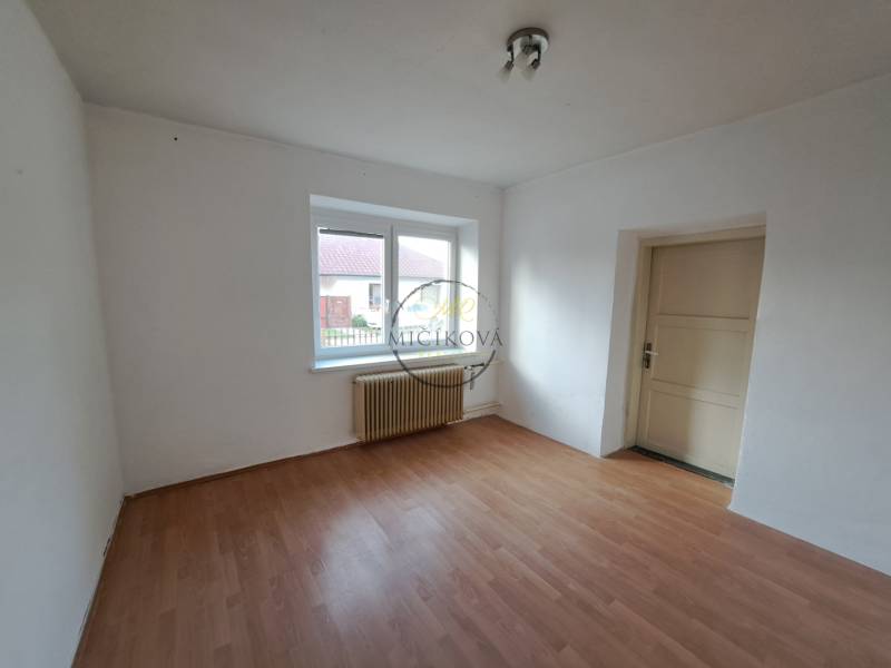 A room in a family house with white walls and a wooden decor floor.