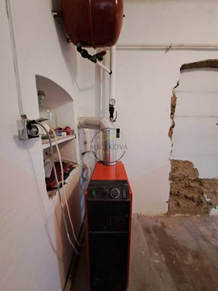 Boiler room in a family house with a boiler and an expansion tank, floor with a wooden decor.