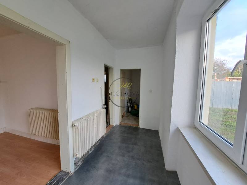 A hallway of a family house with white walls and large windows, floors with various designs.