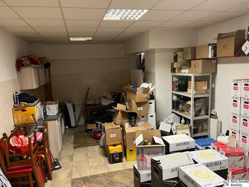 Commercial space with cardboard boxes, furniture, and shelves, wooden decor flooring.