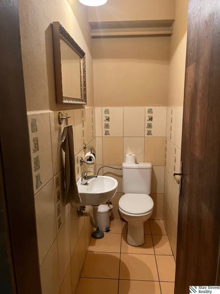 A restroom with a sink, mirror, and ceramic tiles in commercial premises.