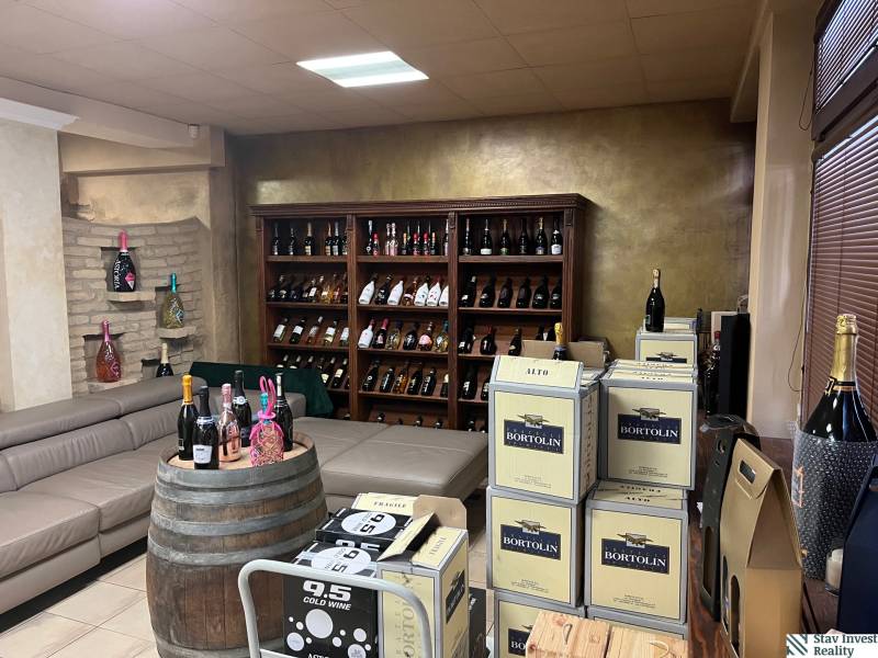 Commercial space with a sofa, a barrel, and a shelf full of wine bottles.