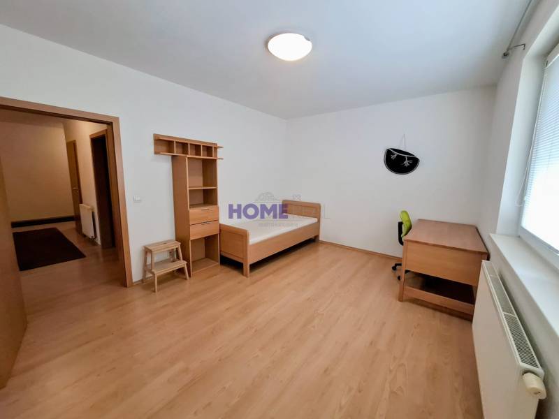 A room in a 3-room apartment with a bed, a table, and a floor with a wooden decor.