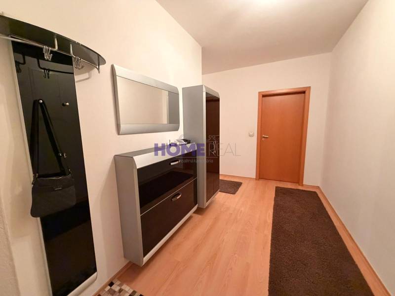 A hallway with a coat rack, mirror, and floor with a wood decor in a 3-room apartment.
