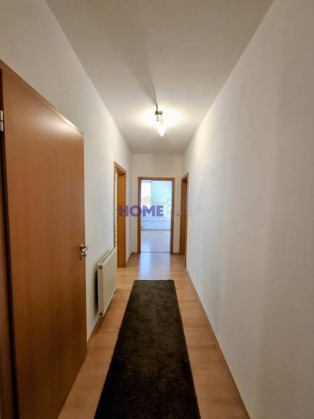 A hallway in a 3-room apartment with a wooden decor floor and a carpet strip.