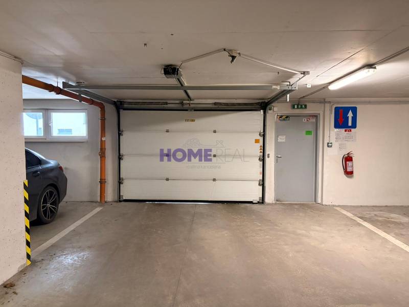 Garage parking with a gate, car, and fire extinguisher, part of a 3-room apartment.