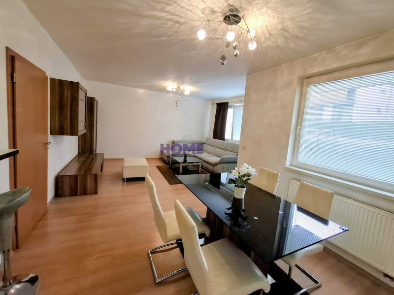 Dining and living area of a 3-room apartment with a wooden decor floor.
