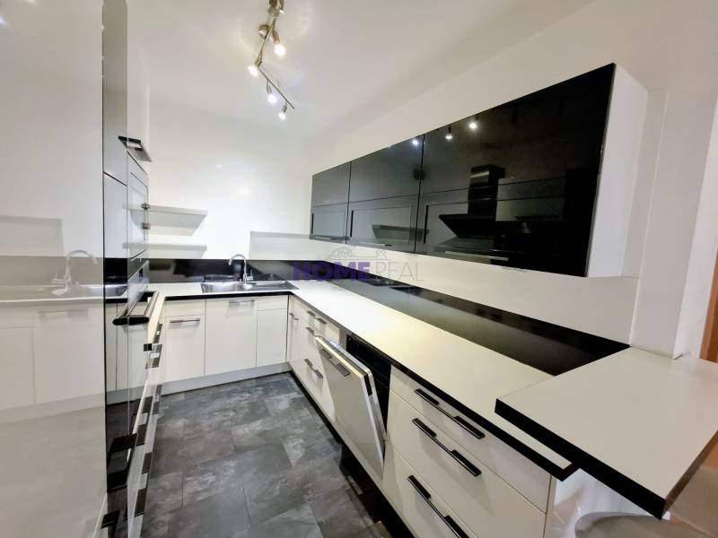 A modern kitchen in a 3-room apartment with black and white cabinets and a glossy floor.