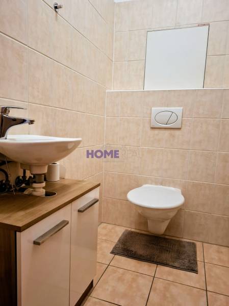 Bathroom in a 3-room apartment with a toilet and sink, tiles and cladding in beige color.
