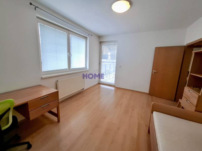 A room in a 3-room apartment with a wooden decor floor, a desk, and a wardrobe.