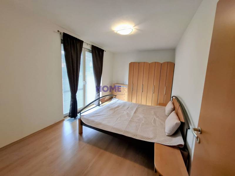 Bedroom in a 3-room apartment with a bed, wardrobe, and wooden decor flooring.