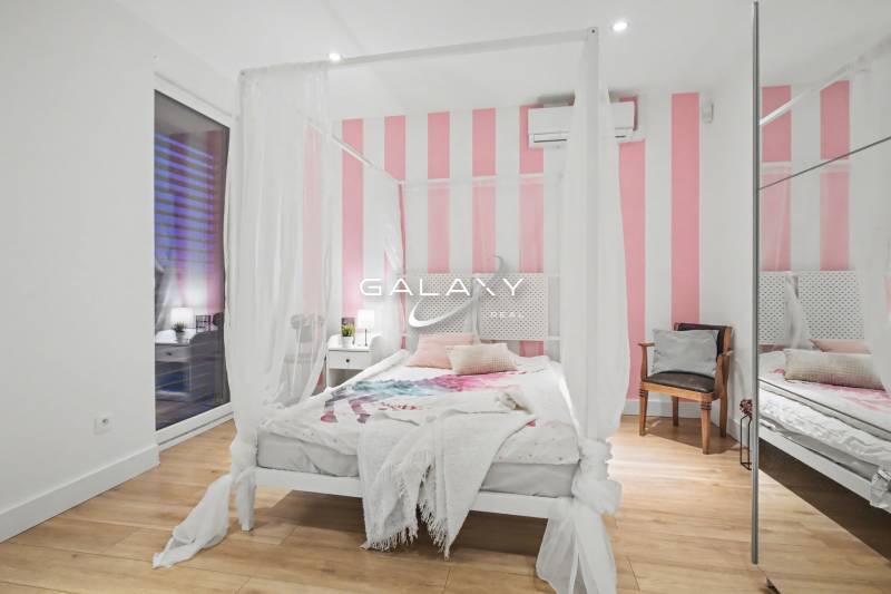 Bedroom with a white-pink wall, canopy, and wooden decor flooring in a family house.