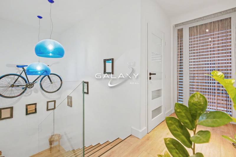 Interior of a family house with a bicycle on the wall, blue lights, and glass railing.