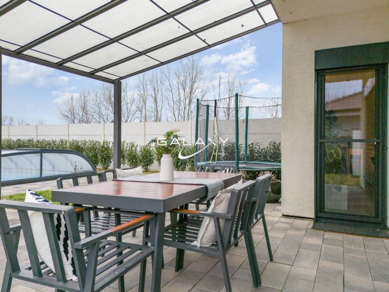 Terrace of a family house in Dunajský Klátov with a seating area, covered swimming pool, and trampoline.