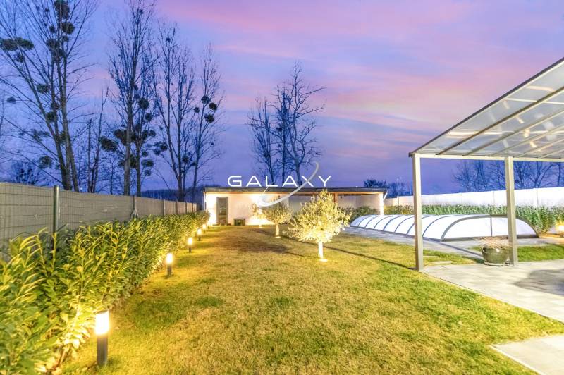 The garden of a family house in Dunajský Klátov with lighting, a swimming pool, and a shelter.