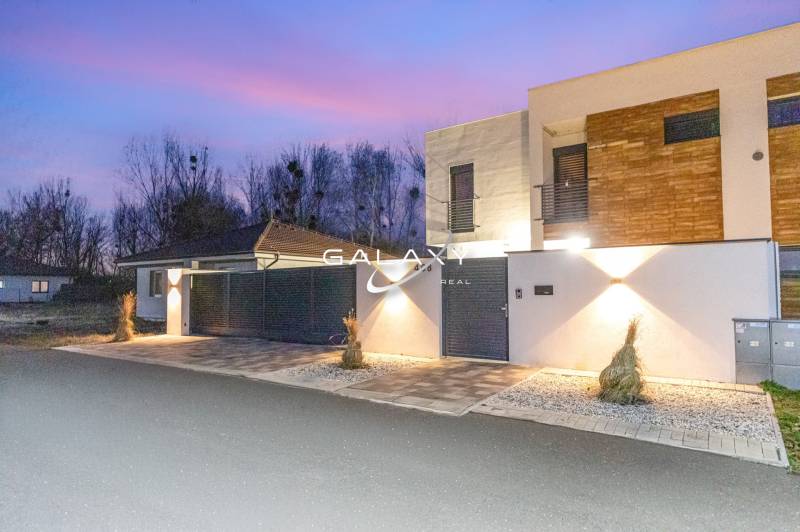 A family house in Dunajský Klátov with a minimalist facade and entrance lighting.