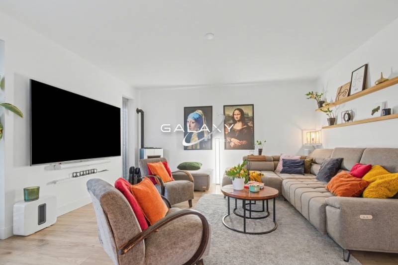 Living room in a family house with comfortable seating, colorful pillows, and a large television.