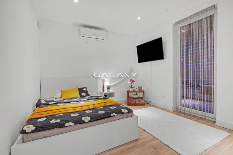Bedroom in a family house with a bed, TV, and floor with wooden decor.
