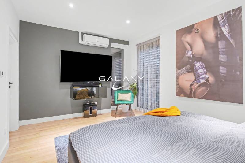 Bedroom with a TV, air conditioning, an armchair, and decorative art in a family house.