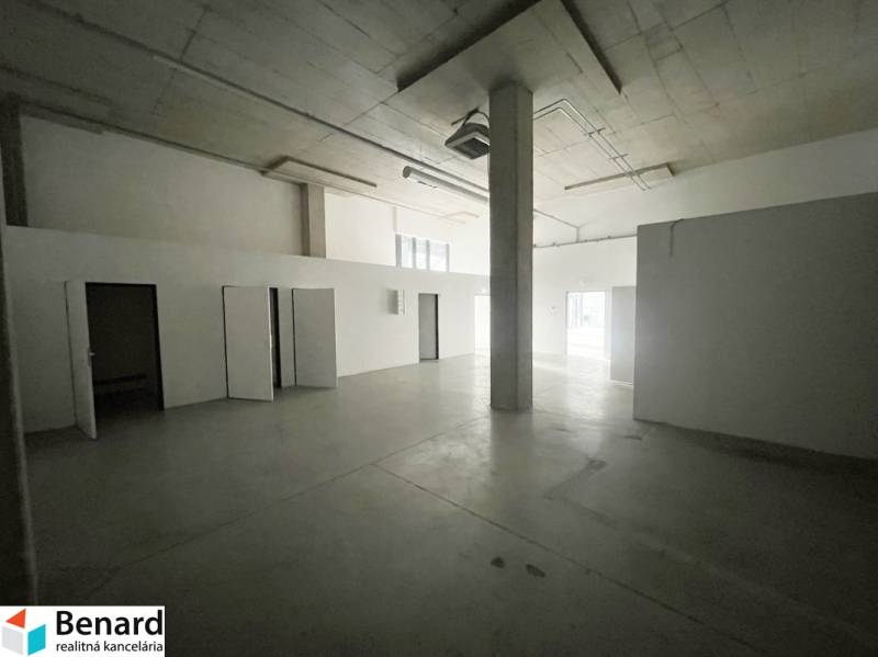 Open space with concrete flooring in commercial premises, white walls and a pillar.