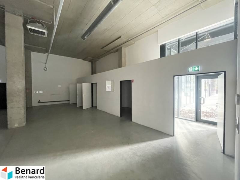 Interior of commercial spaces with concrete flooring and large windows.