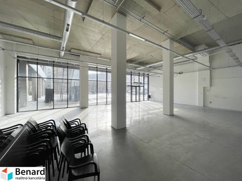 Spacious commercial spaces with large windows and concrete flooring.