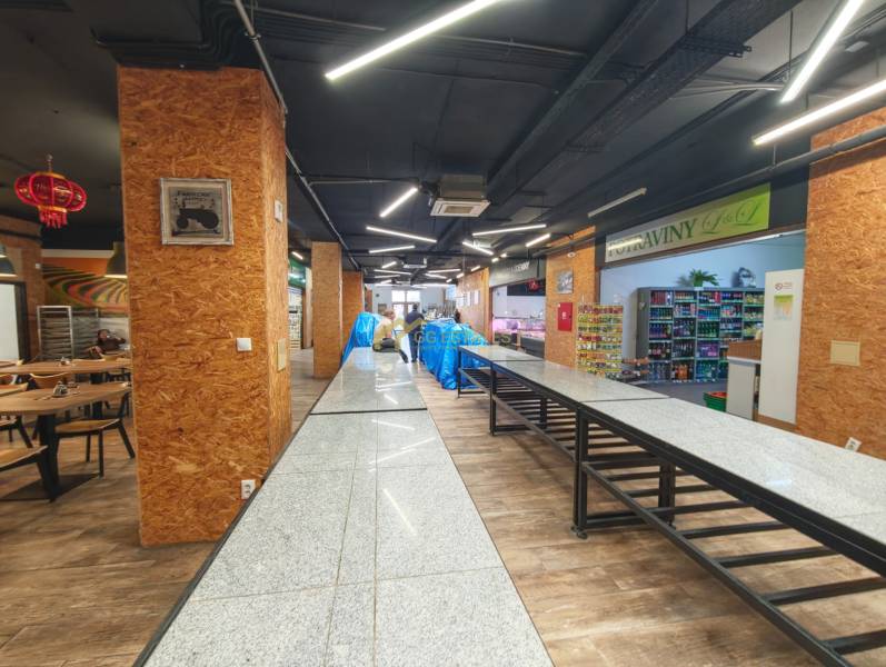 Gastro premises with wooden decor flooring, tables, and food in the background.