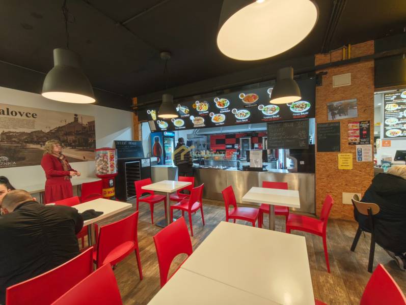 Gastro premises with wooden decor flooring, red chairs, and lights.