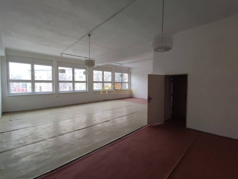 A room in offices with large windows and a wooden decor floor.