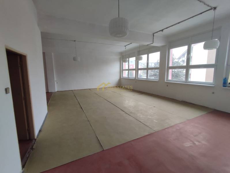 Empty office spaces with large windows and unfinished flooring with a wood decor.