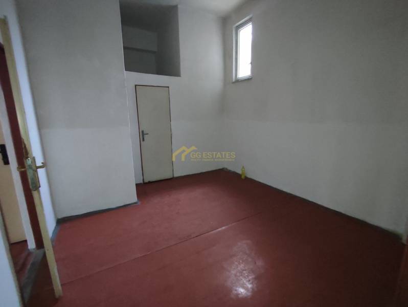 An office with a simple interior and a red floor, a small window, and white walls.