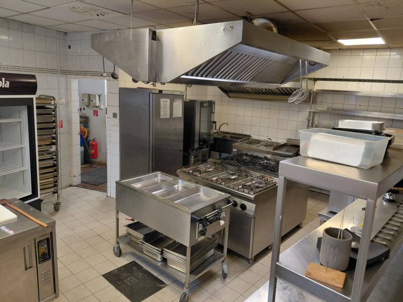 Professional kitchen with stainless steel appliances and equipment in catering spaces.