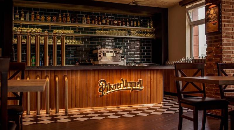 Bar counter with beer taps and decorative lighting in a gastro space with a wooden decor floor.