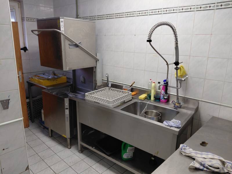 Kitchen washing areas with an industrial dishwasher and stainless steel sink in gastro spaces.