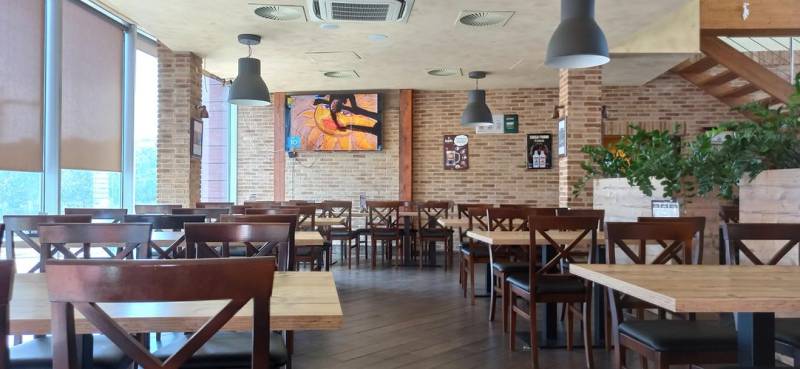 Interior of a gastro space with brick walls, a wooden decor floor, and hanging lamps.