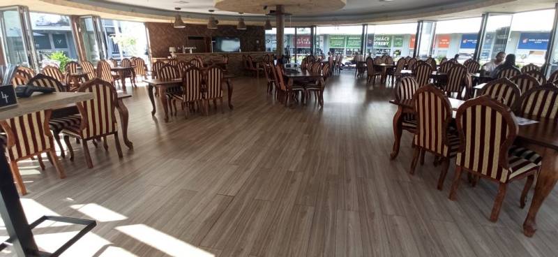 Interior of dining spaces with striped chairs and a wooden-patterned floor.