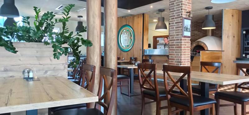 A restaurant with wooden decor and a brick fireplace in the dining area.