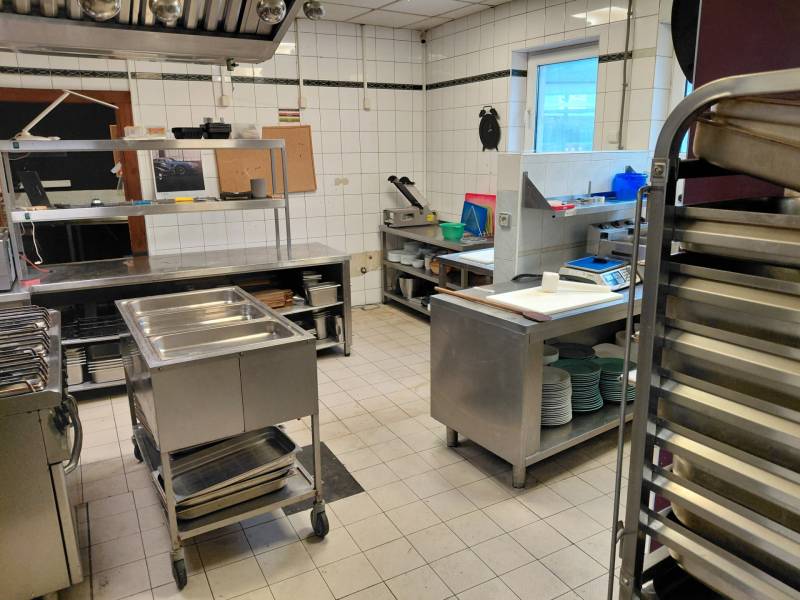 Kitchen gastro spaces with stainless steel equipment and white tiles on the walls.