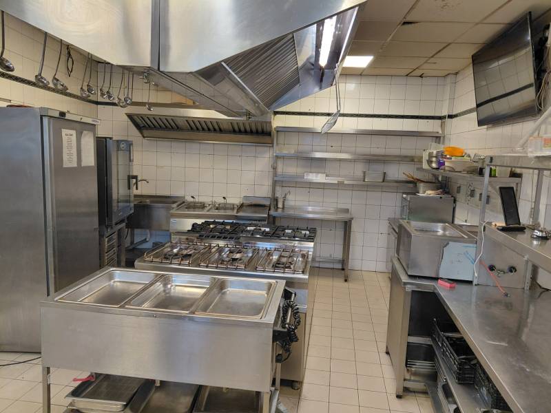 A kitchen space in a gastro facility with stainless steel equipment and white tiles.