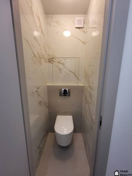 A toilet with marble-patterned tiles in a 2-room apartment.