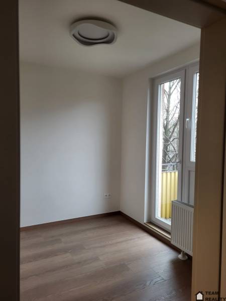 A room in a 2-bedroom apartment, floor with wood decor, large window to the balcony.