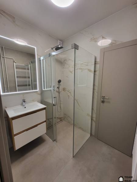 Bathroom with a spacious shower and a sink in a 2-room apartment.